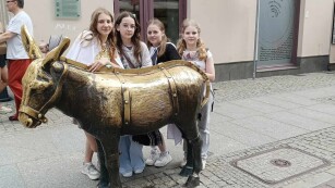 Cztery dziewczynki stoją za metalową rzeźbą osła.