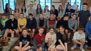Grupa dwudziestu pięciu uczniów piątej klasy siedzi w trzech rzędach nad sobą w Żywym Muzeum Piernika w Toruniu