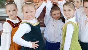 Trzy dziewczynki i dwóch chłopców stoją przebrani w stroje typu renesansowego i wskazują na plakat informujący o trwającym Lubelskim Festiwalu Renesansu.